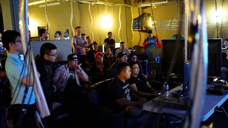 Tournament crowd watching two players on fight sticks, OverKlocked wall logo visible